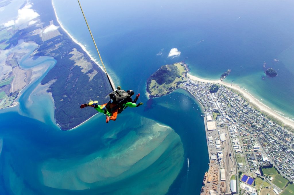 Thrill-seekers enjoying adventure activities in Melbourne, including skydiving over St Kilda, kayaking on the Yarra River, and indoor rock climbing.