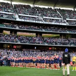Fans at the MCG cheering during the King’s Birthday AFL Match 2025 with Big Freeze 11 banners in the background