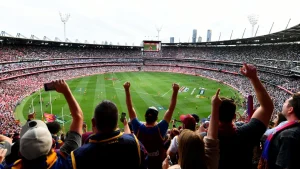Crowds at the AFL Grand Final Parade in Melbourne with players, floats, and the premiership cup on display.